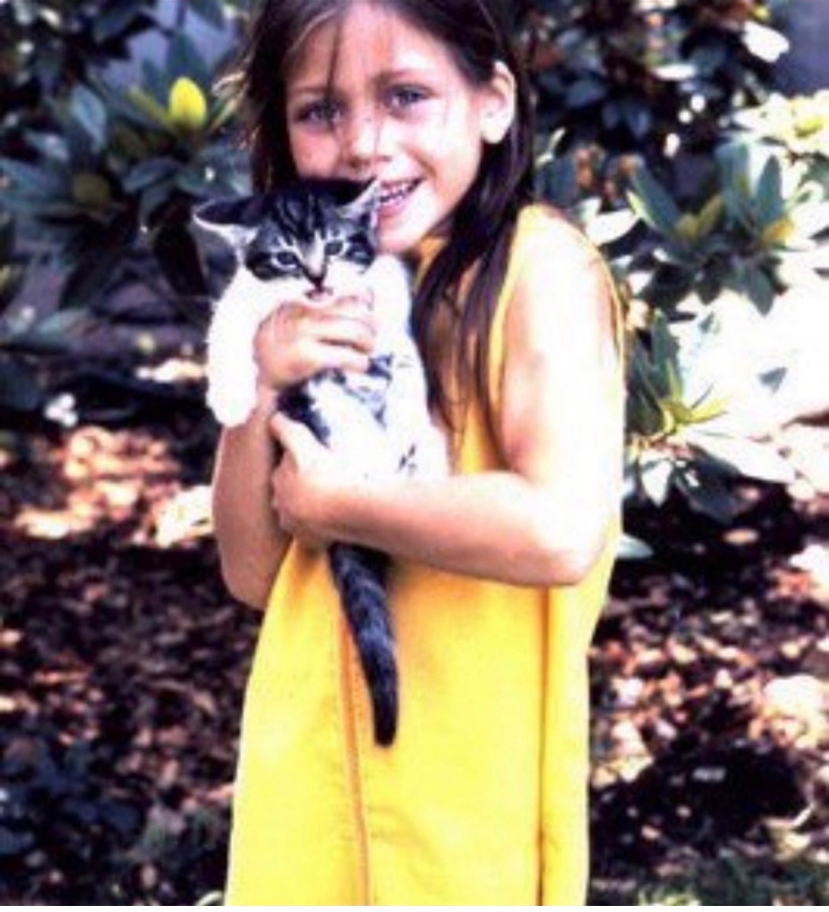 A childhood photograph of Annie Decamp holding a cat in a garden